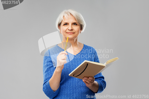Image of senior woman with pencil and diary or notebook