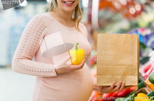 Image of pregnant woman buying vegetables at grocery store