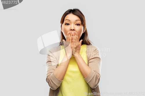 Image of scared asian woman over grey background