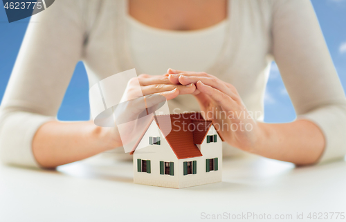 Image of close up of woman protecting house model by hands