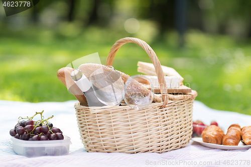 Image of picnic basket, food and wine at summer park