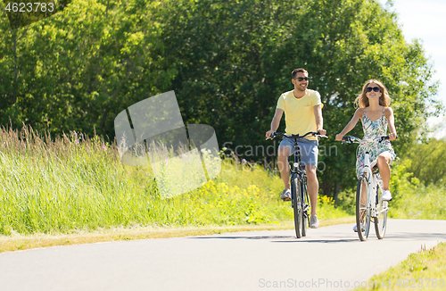 Image of happy young couple riding bicycles in summer