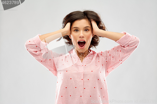 Image of overwhelmed young woman in pajama holding to head