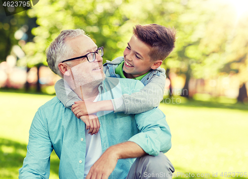 Image of grandfather and grandson hugging at summer park