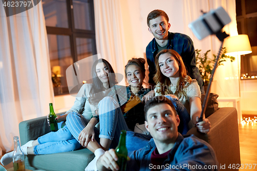 Image of friends taking picture by selfie stick at home