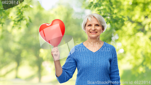 Image of smiling senior woman with red heart shaped balloon