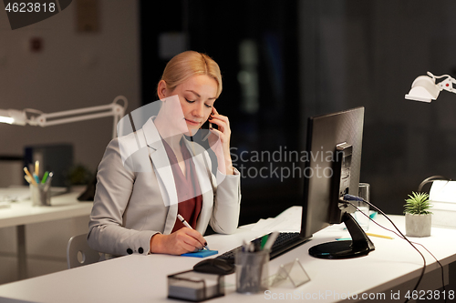 Image of businesswoman calling on sartphone at night office