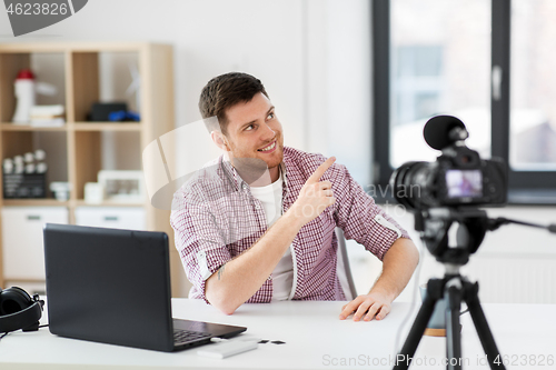 Image of male blogger with camera videoblogging at home