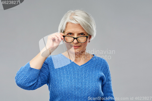 Image of portrait of senior woman looking above glasses