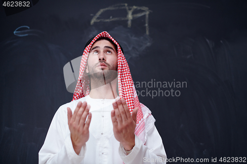 Image of arabian man making traditional prayer to God, keeps hands in pra