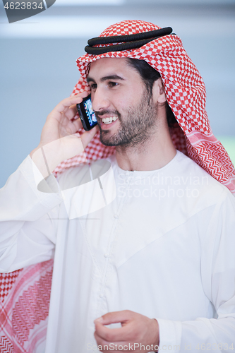 Image of young arabian businessman using smartphone at home