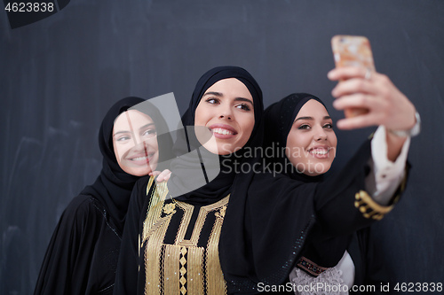 Image of muslim women taking selfie picture in front of black chalkboard