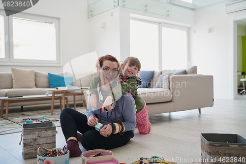 Image of Mother and little girl daughter playing with jewelry  at home