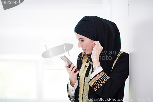 Image of young modern muslim business woman using smartphone at home