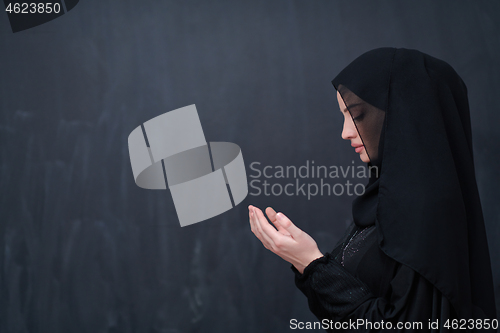 Image of muslim woman making traditional prayer to God in front of black 