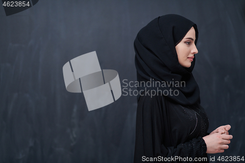 Image of portrait of beautiful muslim woman in front of black chalkboard
