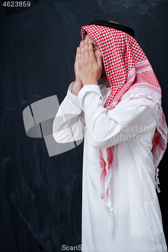 Image of arabian man making traditional prayer to God, keeps hands in pra