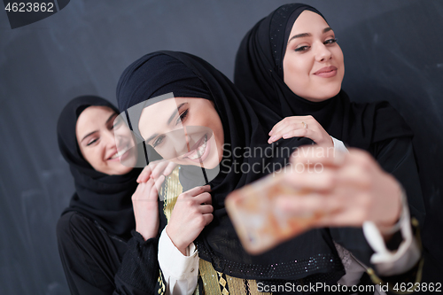 Image of muslim women taking selfie picture in front of black chalkboard