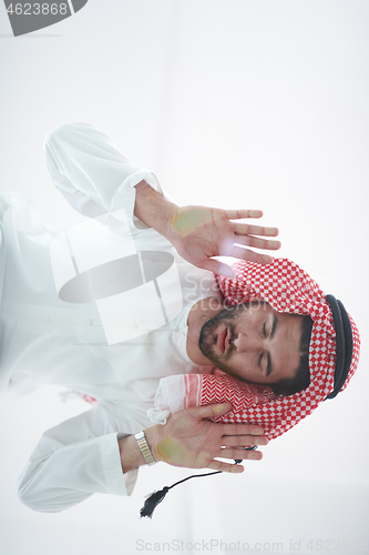 Image of young arabian muslim man praying on the glass floor at home