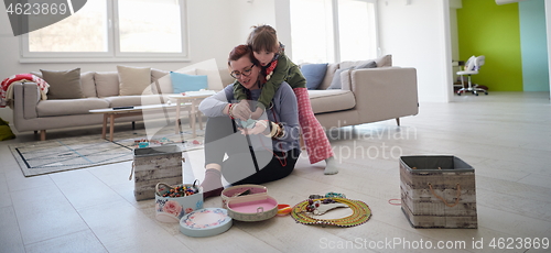 Image of Mother and little girl daughter playing with jewelry  at home