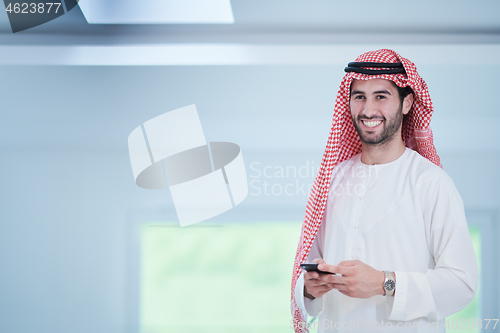 Image of young arabian businessman using smartphone at home