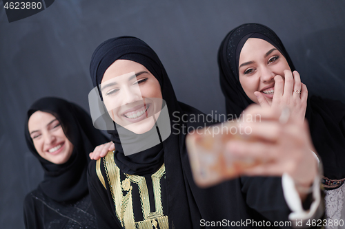 Image of muslim women taking selfie picture in front of black chalkboard