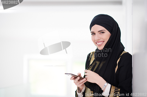 Image of young modern muslim business woman using smartphone at home