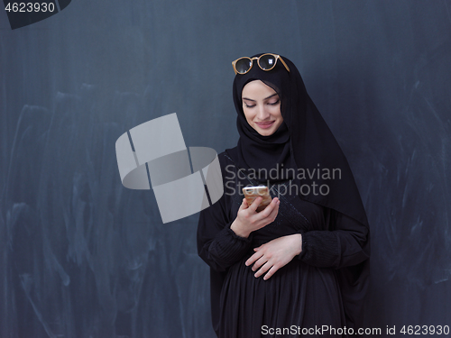 Image of young muslim woman wearing sunglasses using smartphone