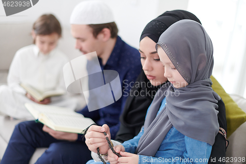 Image of muslim family reading Quran and praying at home