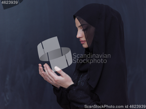Image of muslim woman making traditional prayer to God in front of black 