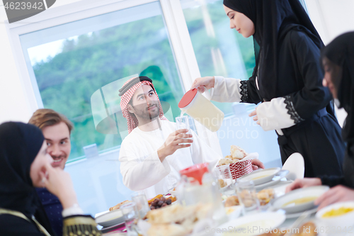 Image of Muslim family having Iftar dinner drinking water to break feast