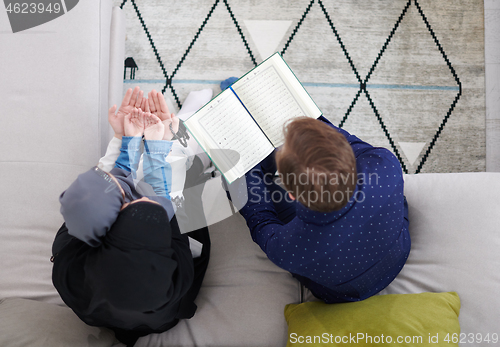 Image of muslim family reading Quran and praying at home top view