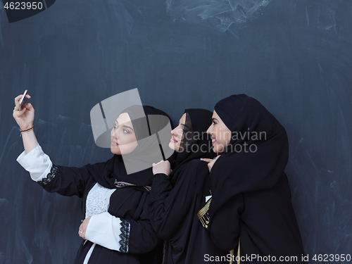 Image of muslim women taking selfie picture in front of black chalkboard