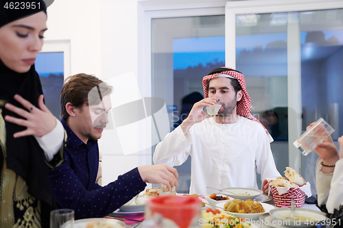 Image of Muslim family having Iftar dinner drinking water to break feast