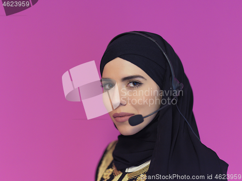 Image of portrait of muslim woman with headset on pink background