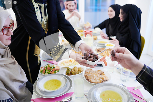 Image of Muslim family having Iftar dinner eating dates to break feast