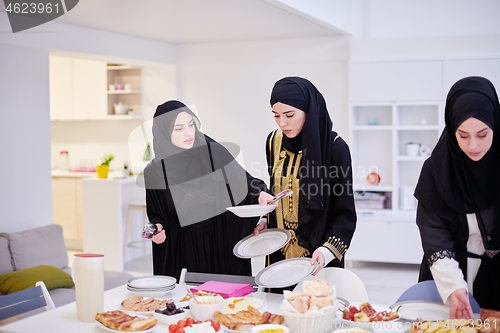 Image of young muslim girls serving food on the table for iftar dinner