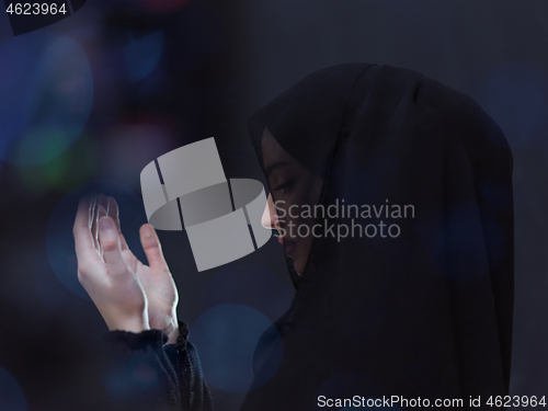 Image of muslim woman making traditional prayer to God in front of black 