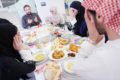 Image of traditional muslim family praying before iftar dinner