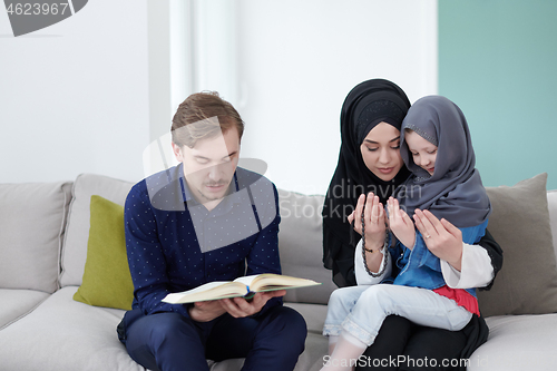 Image of muslim family reading Quran and praying at home