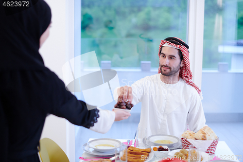 Image of Muslim family having Iftar dinner eating dates to break feast