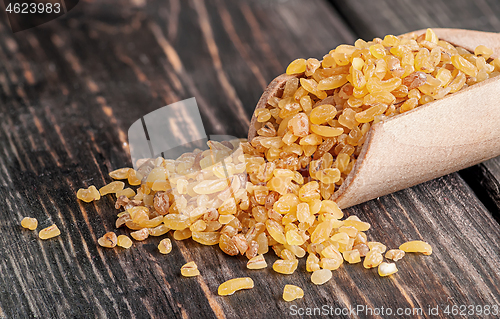 Image of Bulgur in wooden scoop closeup 