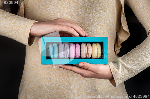 Image of Female hands hold macaroons in box