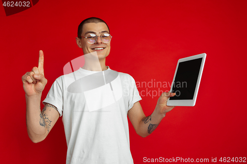 Image of Caucasian young man\'s portrait on red studio background with copyspace - emotional and expressive