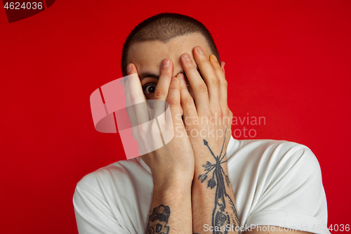 Image of Caucasian young man\'s portrait on red studio background, emotinal and expressive