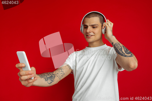 Image of Caucasian young man\'s portrait on red studio background with copyspace - emotional and expressive