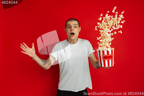 Image of Caucasian young man\'s portrait on red studio background, emotinal and expressive, cinema concept