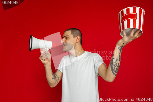 Image of Caucasian young man\'s portrait on red studio background, emotinal and expressive, cinema concept