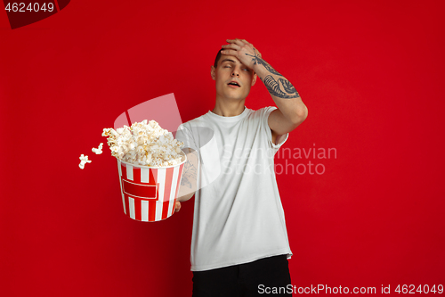 Image of Caucasian young man\'s portrait on red studio background, emotinal and expressive, cinema concept