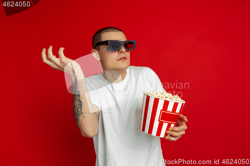 Image of Caucasian young man\'s portrait on red studio background, emotinal and expressive, cinema concept